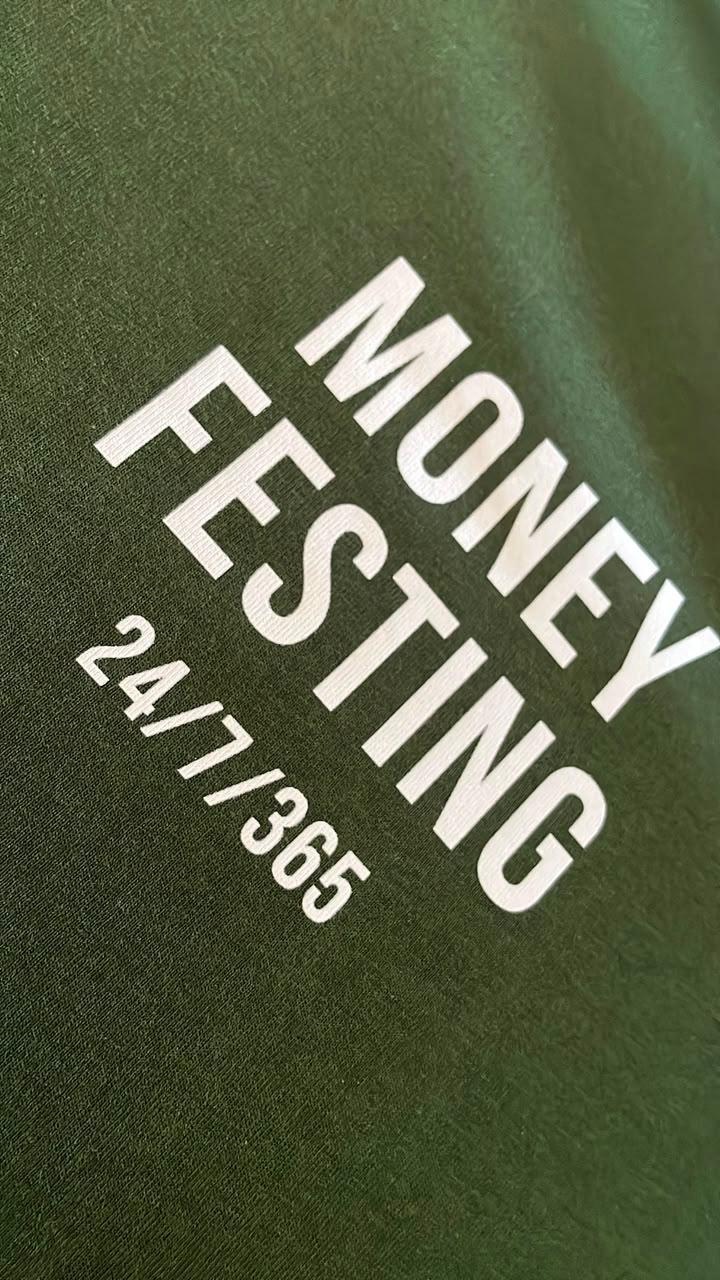 Close-up of the Money Festing 24/7/365 print on a bottle-green tee